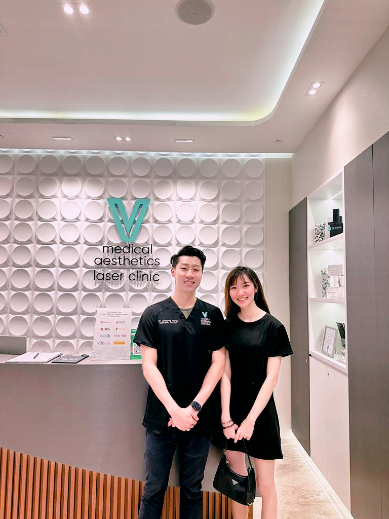 Two staff members smiling at the reception desk of V Medical Aesthetics & Laser Clinic.