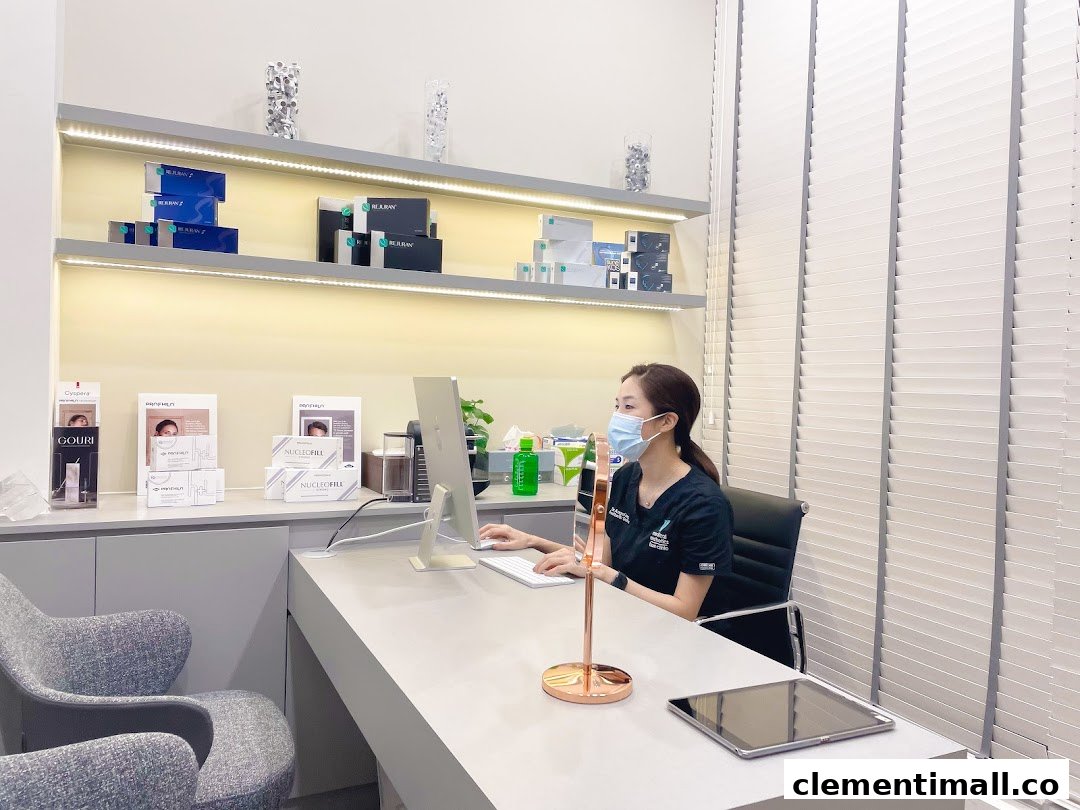 A clinic staff member at a desk with aesthetic products displayed on illuminated shelves.