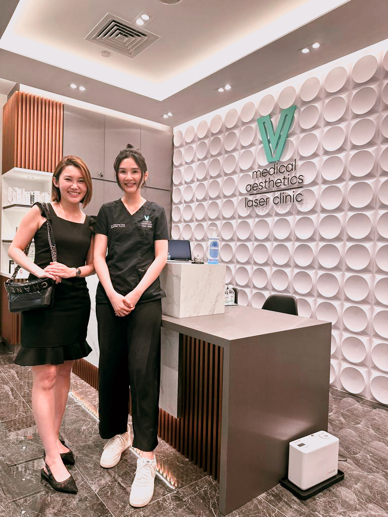 Two women stand smiling in the modern reception area of V Medical Aesthetics & Laser Clinic.