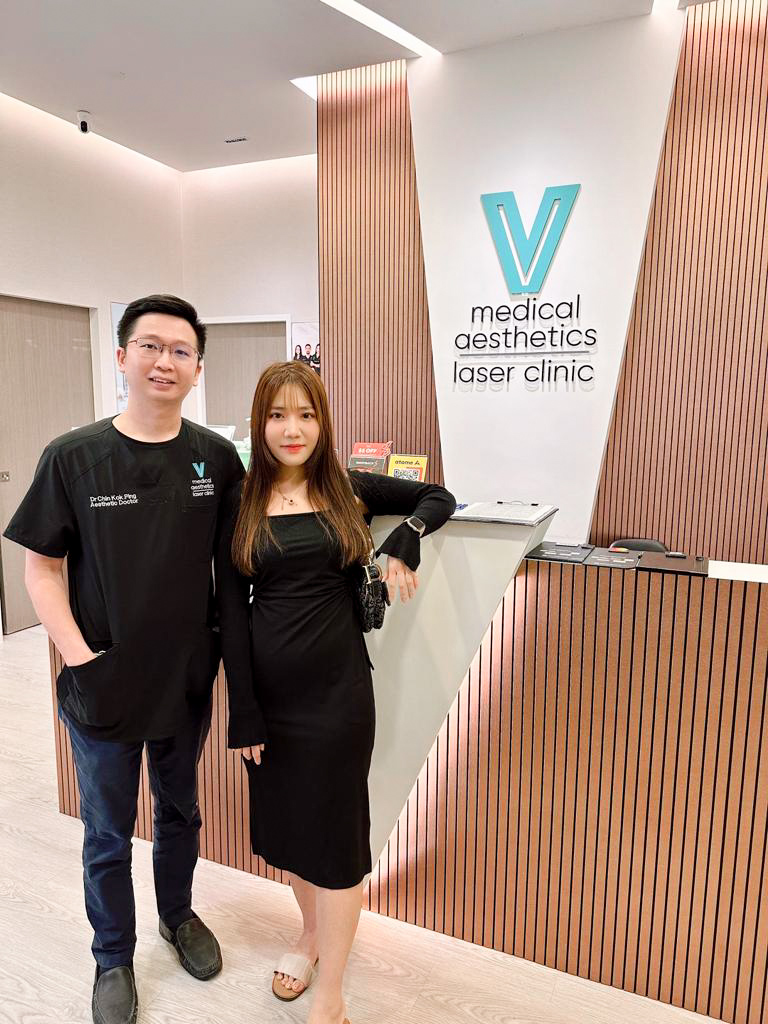 Two individuals stand at the reception of V Medical Aesthetics Laser Clinic.
