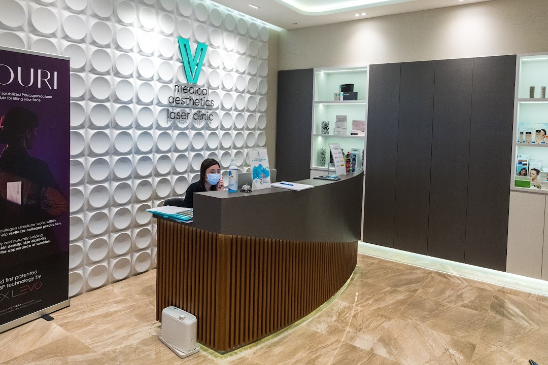 A modern reception area of V Medical Aesthetics & Laser Clinic with a staff member at the desk.