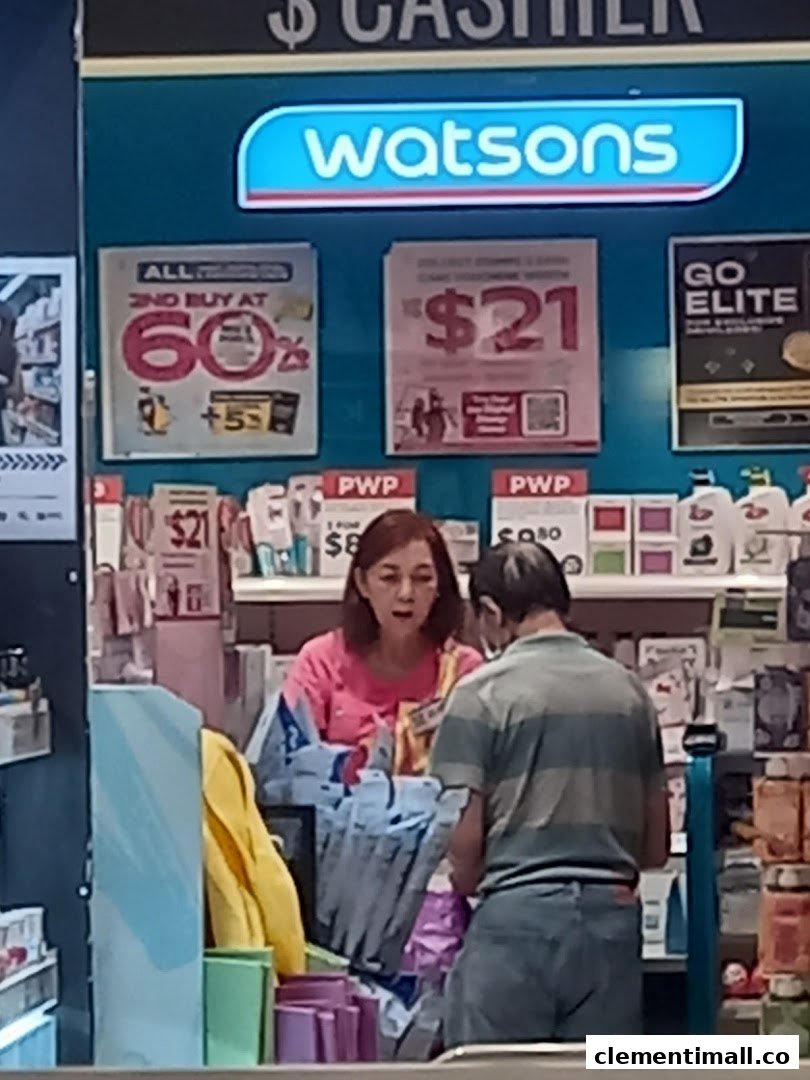 A Watsons pharmacy cashier area with staff assisting a customer, showing promotional signage.