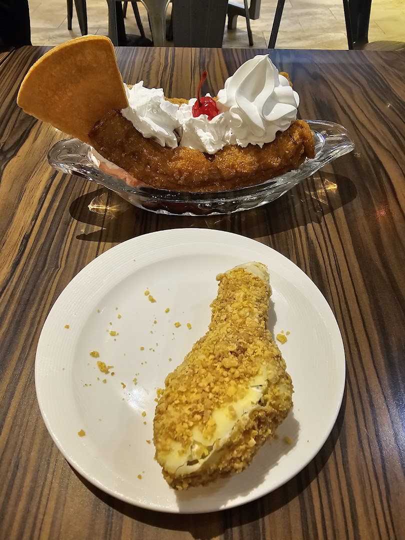 Delicious fried desserts, including a banana split, served on a wooden table.