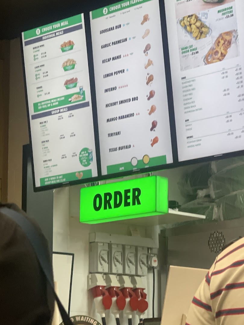 Digital menu boards at Wingstop displaying individual and group meals, along with various wing flavors and sides.