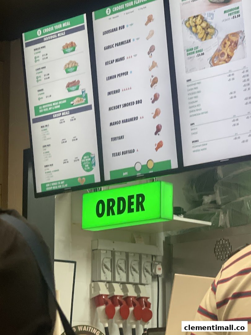 Digital menu boards at Wingstop displaying individual and group meals, along with various wing flavors and sides.