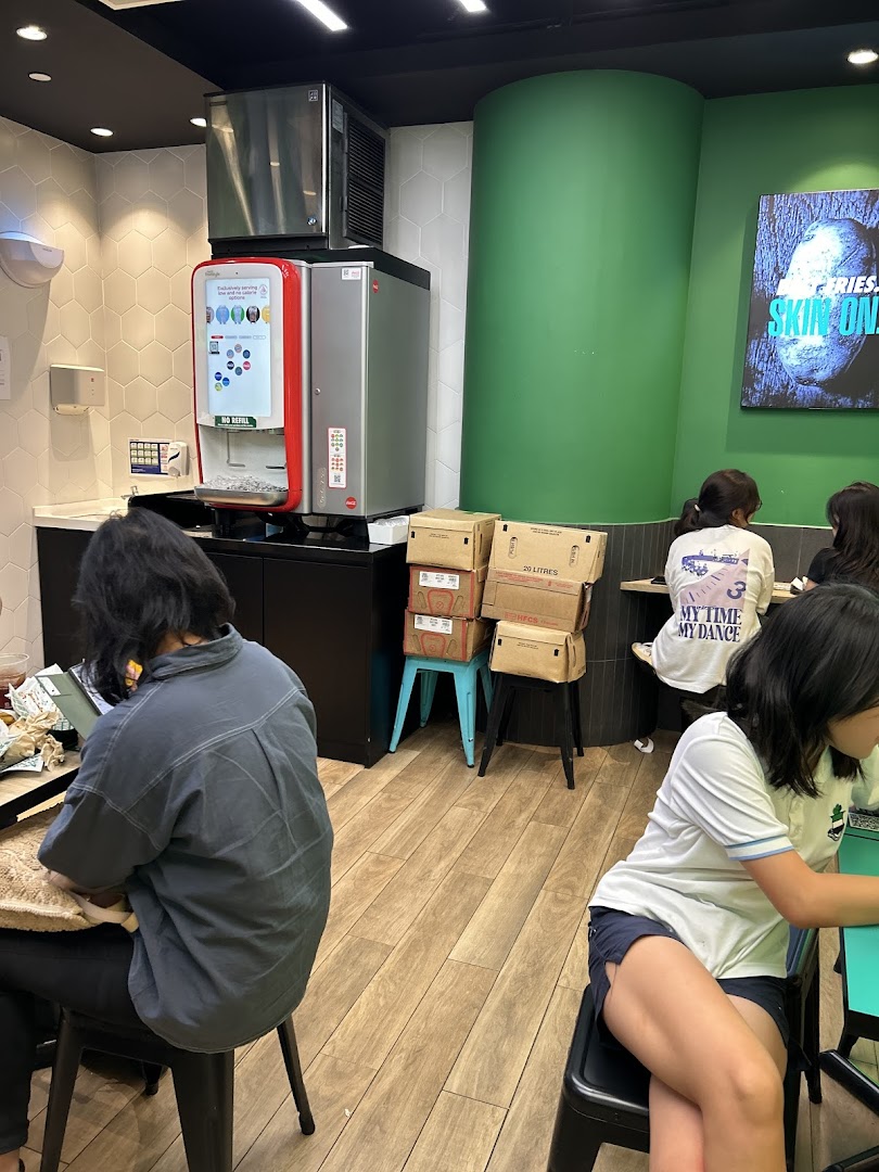 Customers seated inside Wingstop, featuring a soda fountain and a vibrant green wall.