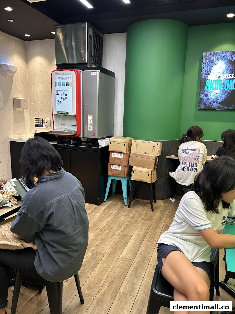 Customers seated inside Wingstop, featuring a soda fountain and a vibrant green wall.