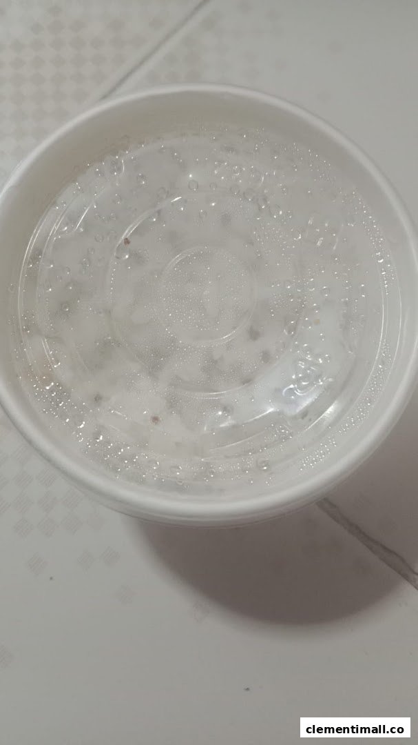 A white takeout container with a clear, condensation-covered lid, likely holding food.