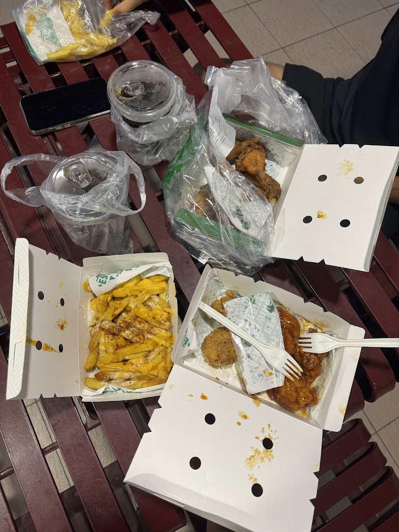 Delicious Wingstop takeout featuring cheesy fries, saucy chicken wings, and drinks on a bench.