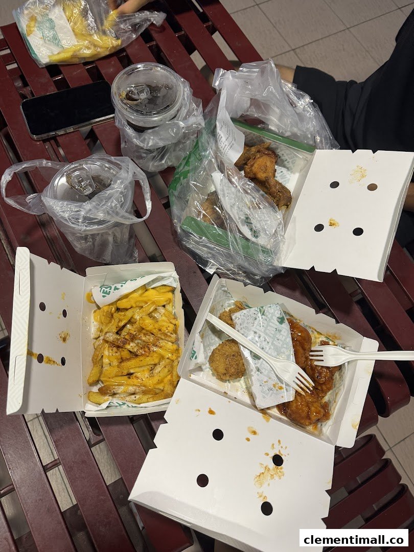 Delicious Wingstop takeout featuring cheesy fries, saucy chicken wings, and drinks on a bench.
