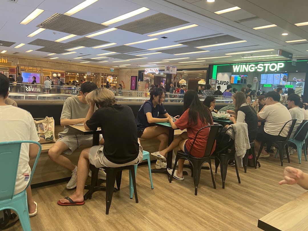 Diners enjoying meals in a bustling food court with Wingstop visible in the background.