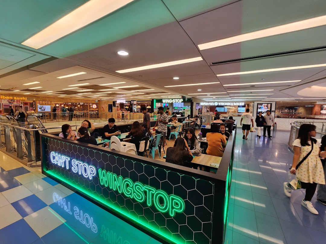 Wingstop dining area in a bustling mall food court with customers enjoying their meals.