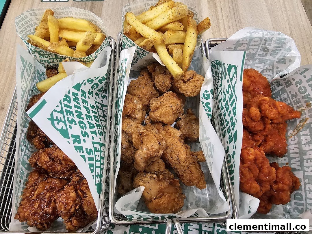 Three baskets of Wingstop chicken wings, tenders, and fries on a table.