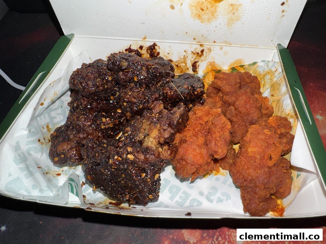 A box of Wingstop chicken featuring dark, saucy wings and crispy, red boneless chicken.