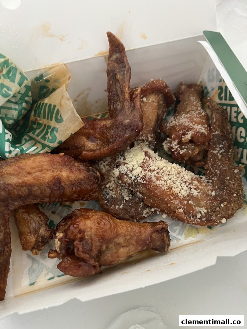 Close-up of delicious Wingstop chicken wings in a takeout box, some with parmesan.