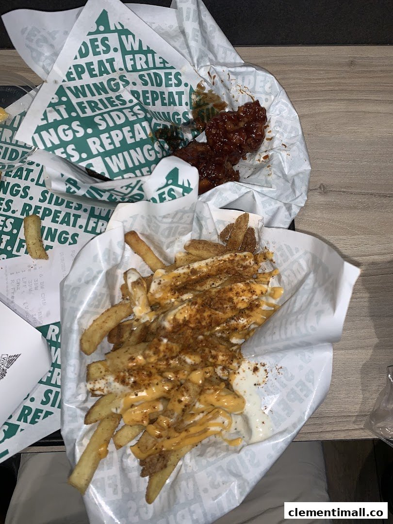 Two servings of Wingstop food, featuring saucy wings and loaded fries in branded paper.