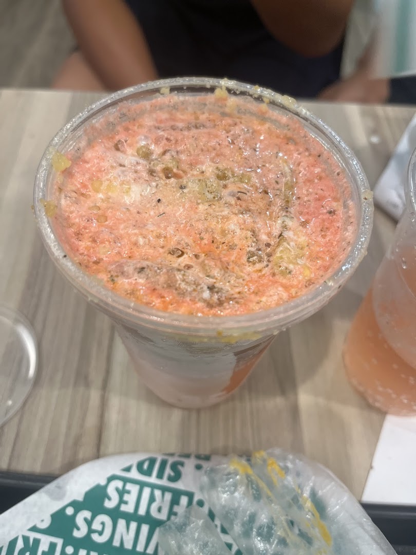 A close-up of a vibrant, foamy beverage in a clear cup, likely from Wingstop.