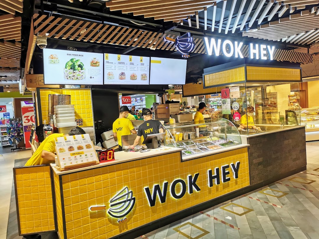 WOK HEY food stall in a mall, featuring staff, counter, and overhead menu displays.