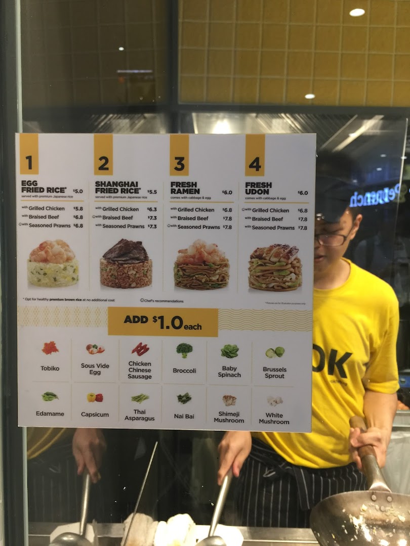 A menu board for WOK HEY displaying customizable fried rice and noodle dishes with a chef cooking in the background.