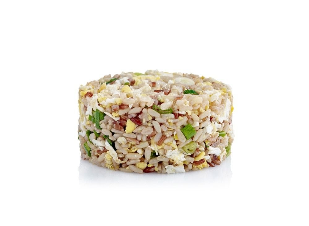 A close-up studio shot of a cylindrical portion of mixed grain fried rice with egg and spring onions.