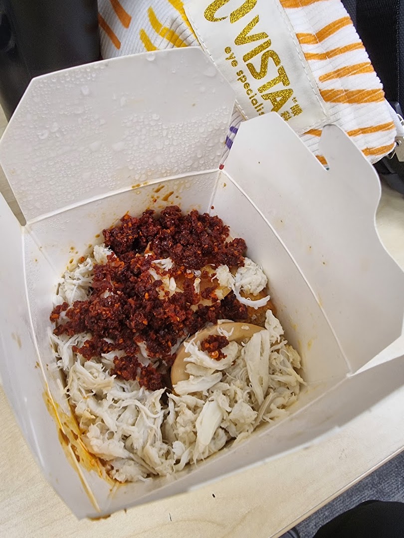 A close-up of a Wok Hey takeaway box filled with rice, shredded meat, and chili flakes.