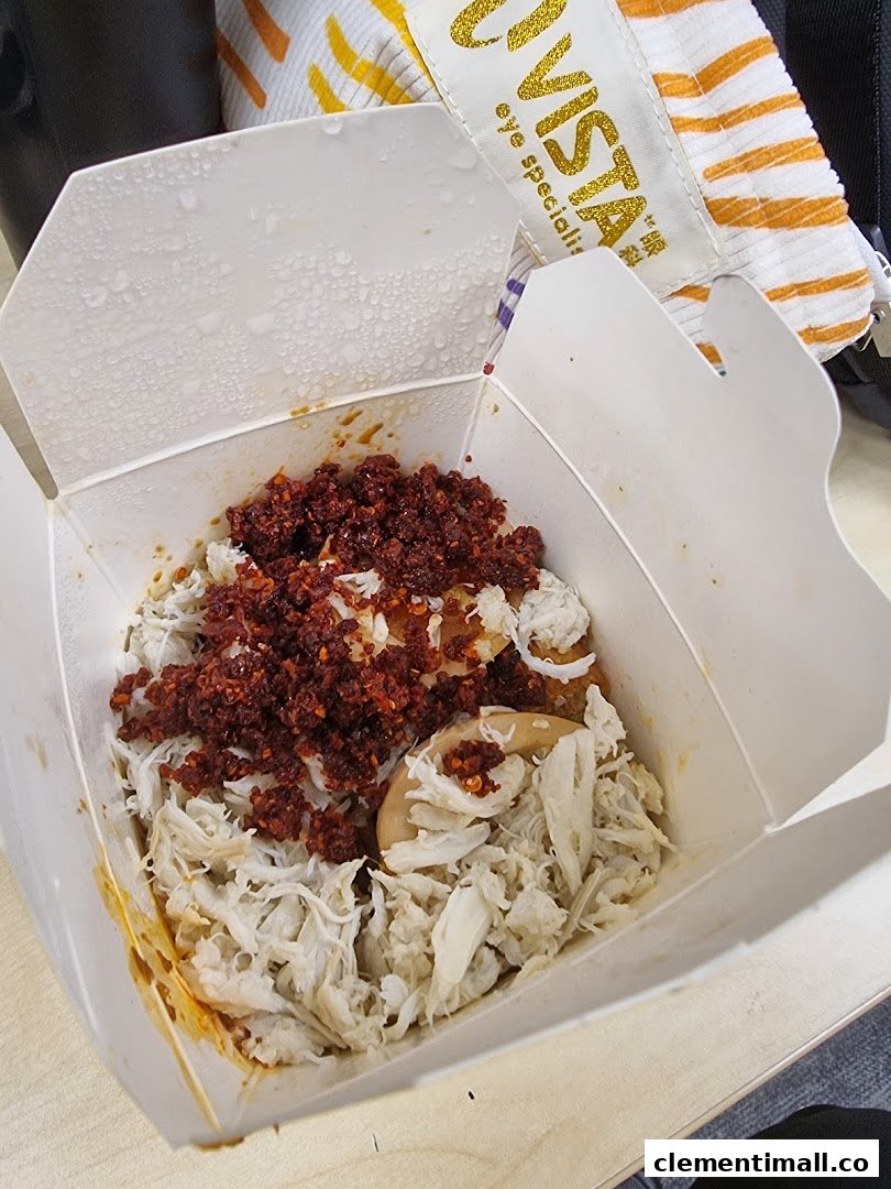 A close-up of a Wok Hey takeaway box filled with rice, shredded meat, and chili flakes.