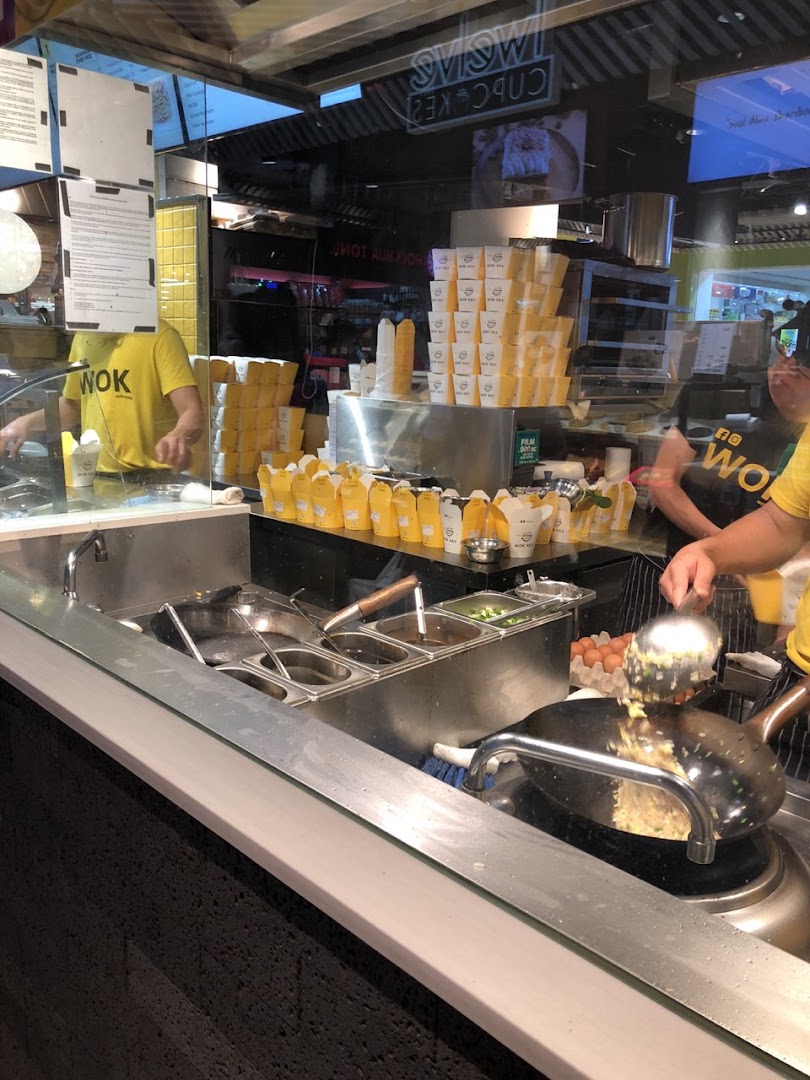 Chefs at WOK HEY prepare fresh wok-fried dishes, showcasing the open kitchen and numerous takeaway boxes.