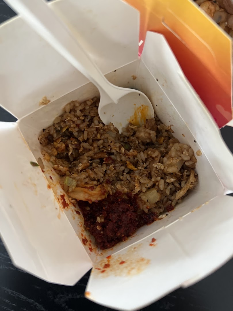 A close-up of delicious fried rice with chili paste in a Wok Hey takeaway box.