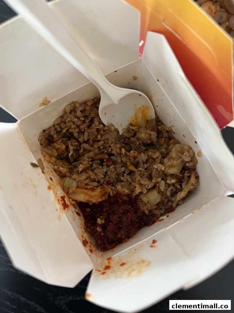 A close-up of delicious fried rice with chili paste in a Wok Hey takeaway box.