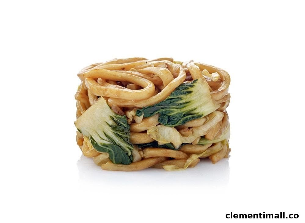 A studio shot of stir-fried noodles with bok choy, presented on a white background.