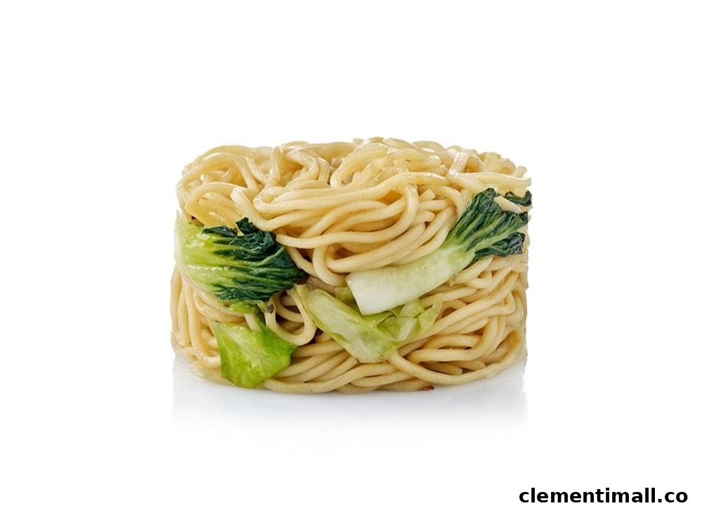 A block of cooked noodles with green bok choy on a white background.