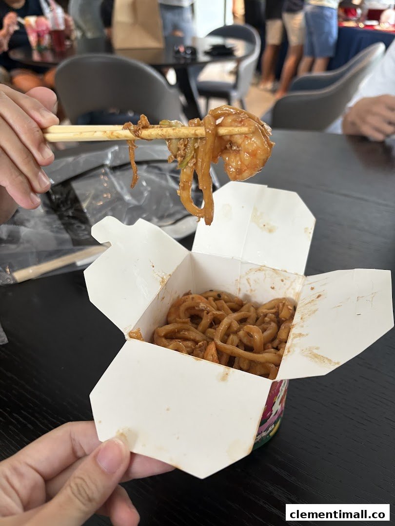 A person holds chopsticks with noodles and shrimp from a WOK HEY take-out box.