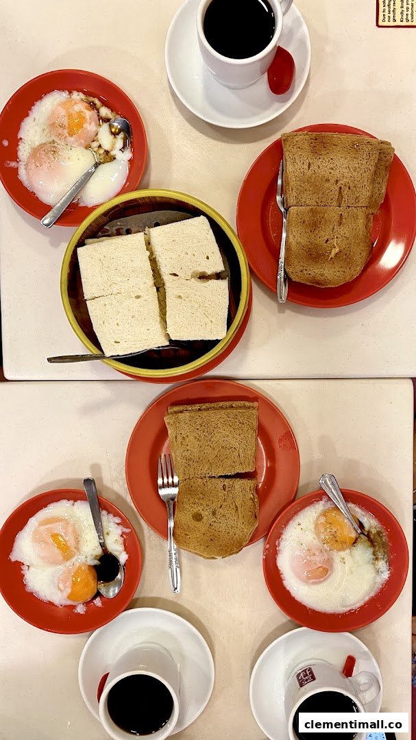 A table laden with traditional Singaporean breakfast: kaya toast, soft-boiled eggs, and coffee.