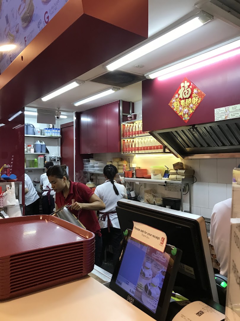 Staff prepare traditional kaya toast and beverages behind the counter at Ya Kun Kaya Toast, showcasing the bustling kitchen.