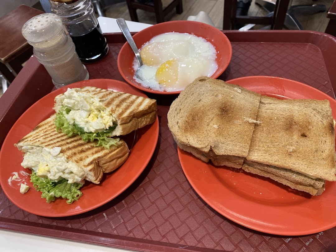 A classic Ya Kun Kaya Toast breakfast set featuring toasted bread, egg salad sandwich, and soft-boiled eggs.
