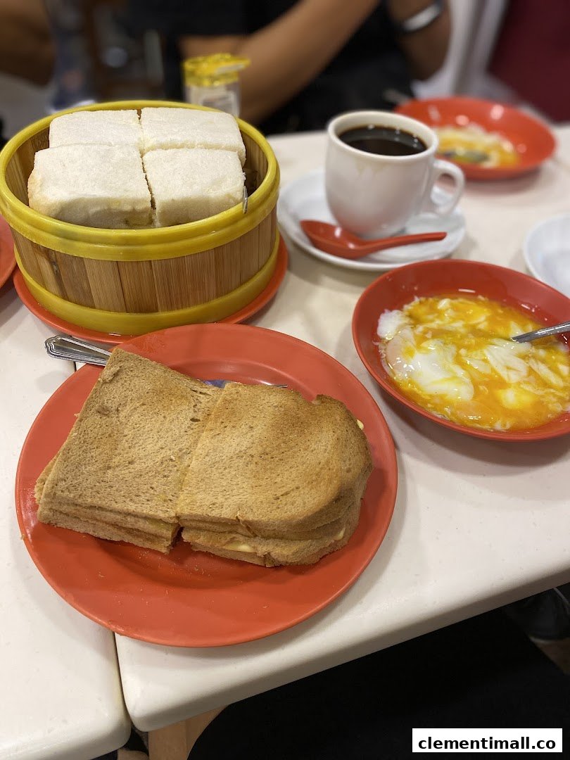 A table set with traditional kaya toast, soft-boiled eggs, and a cup of coffee at Ya Kun Kaya Toast.