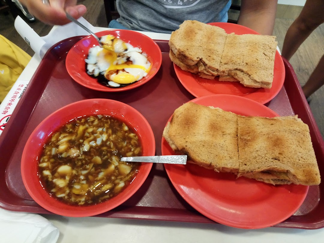 A tray featuring Ya Kun Kaya Toast's signature kaya toast, soft-boiled eggs, and a dessert, ready to be enjoyed.
