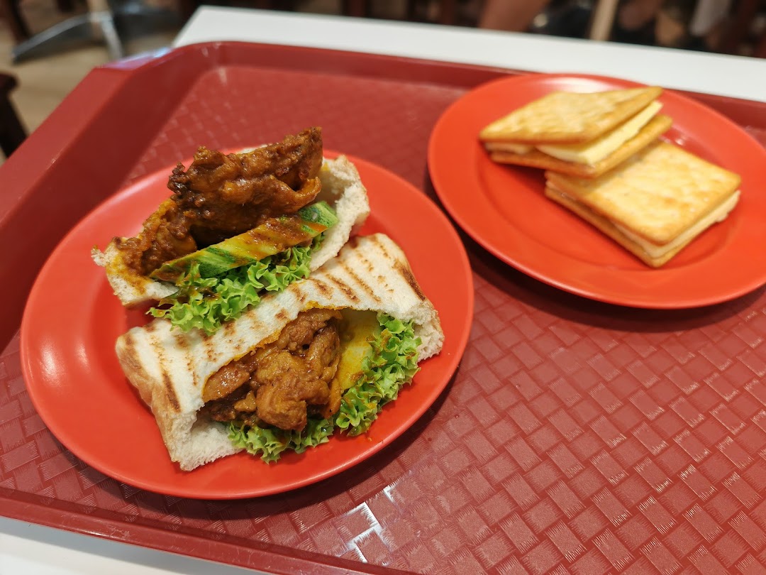 A close-up of a savory toastie with chicken and salad, alongside sweet cream crackers on a red tray.