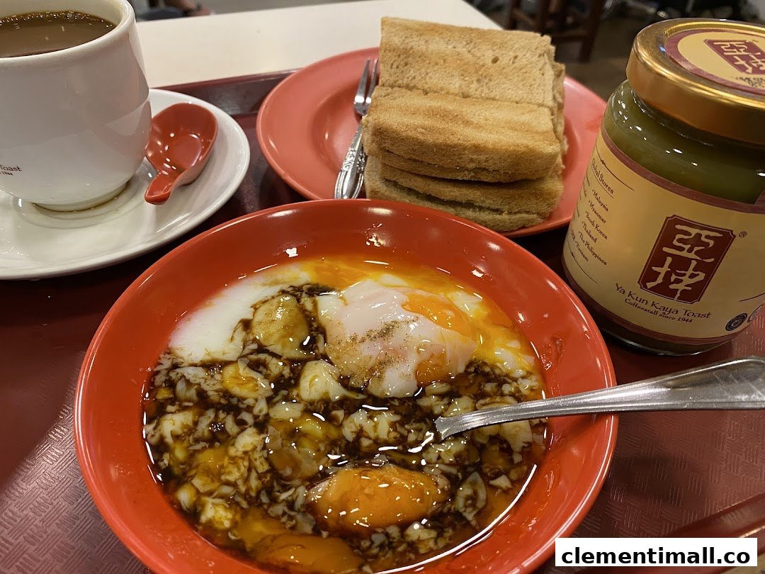 A classic Ya Kun Kaya Toast breakfast set featuring soft-boiled eggs, kaya toast, coffee, and a jar of kaya spread.
