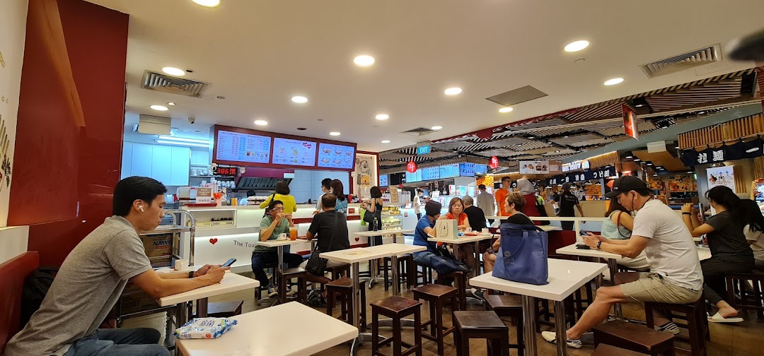 Customers enjoying meals and drinks inside Ya Kun Kaya Toast, featuring a bustling counter and dining area.