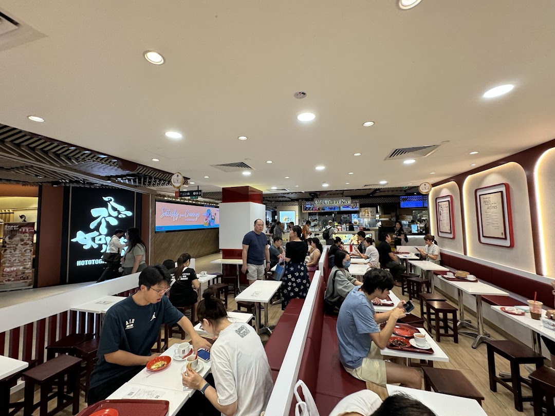 The interior of Ya Kun Kaya Toast, showing customers seated at tables enjoying their meals in a bustling setting.