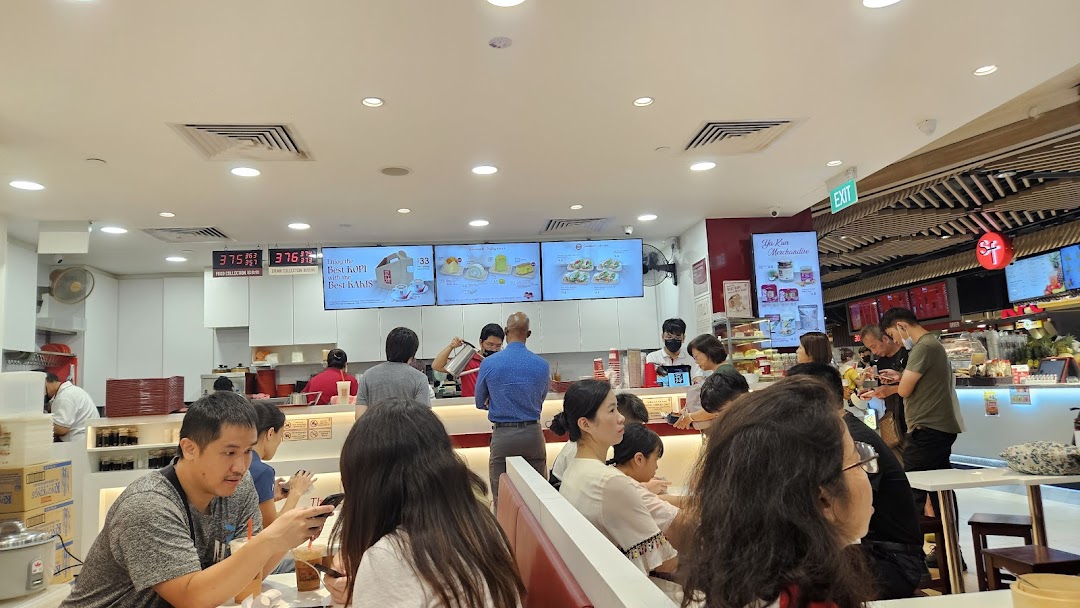 Customers enjoy traditional Singaporean breakfast and snacks at Ya Kun Kaya Toast, with staff preparing orders.