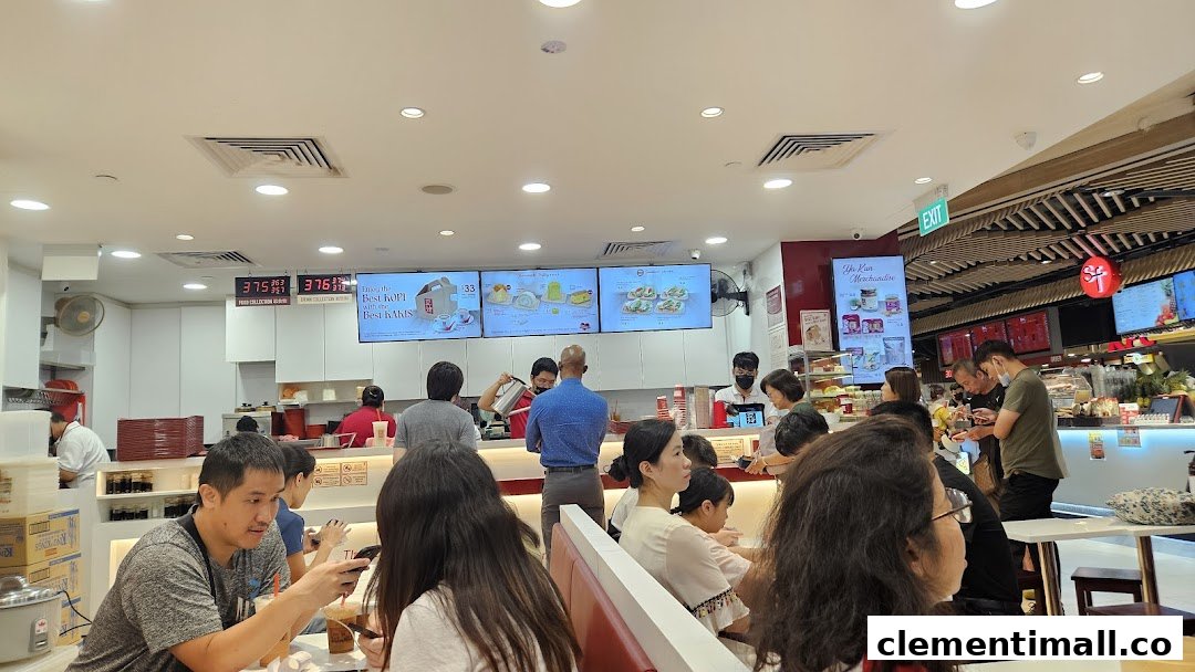 Customers enjoy traditional Singaporean breakfast and snacks at Ya Kun Kaya Toast, with staff preparing orders.