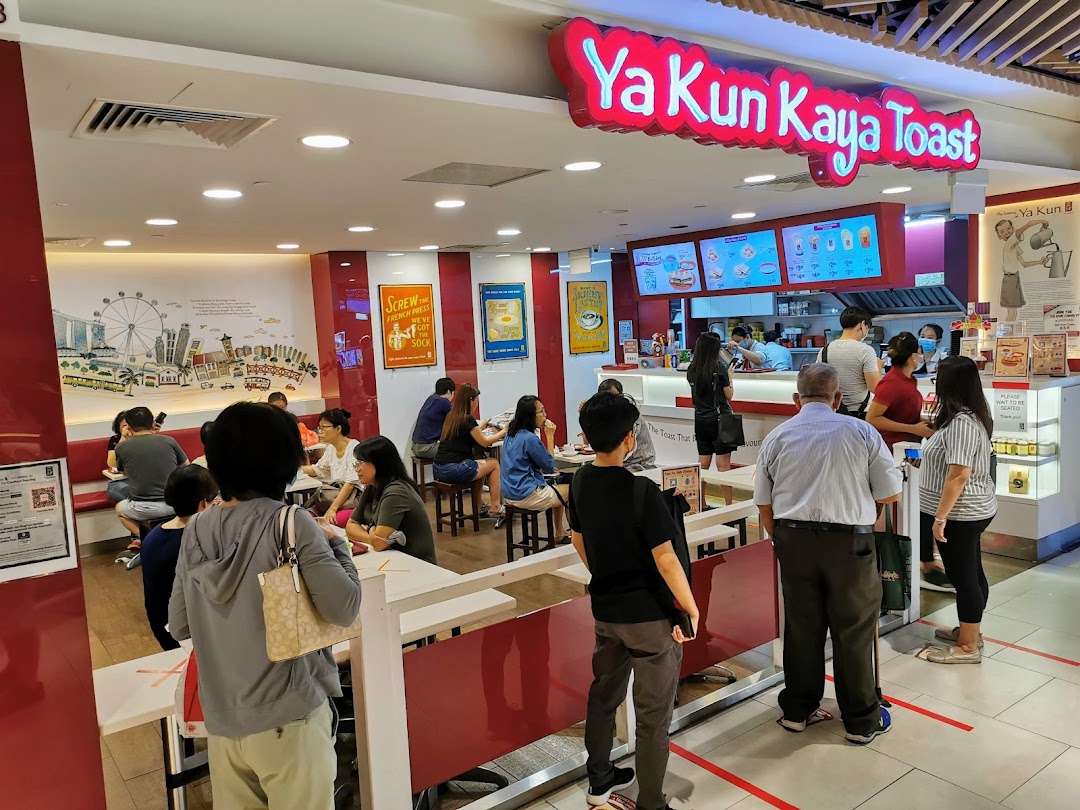A bustling interior view of Ya Kun Kaya Toast, showing customers ordering and dining in a vibrant setting.