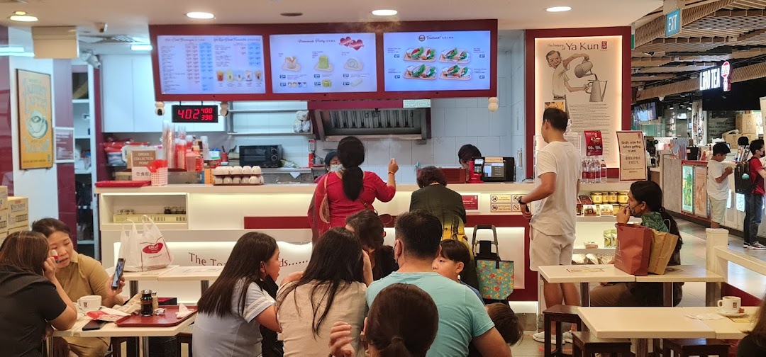 Customers and staff at Ya Kun Kaya Toast, with menu boards and a busy counter area.