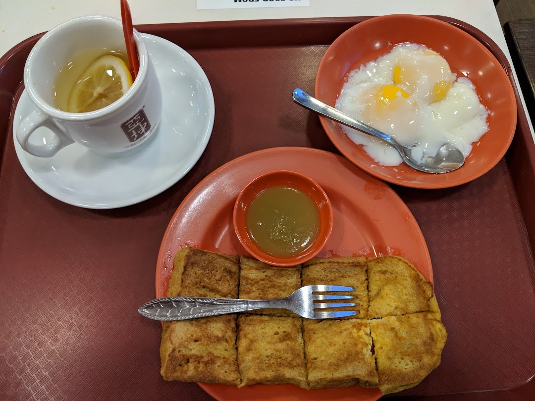A classic Ya Kun Kaya Toast breakfast set featuring kaya toast, soft-boiled eggs, and lemon tea on a tray.