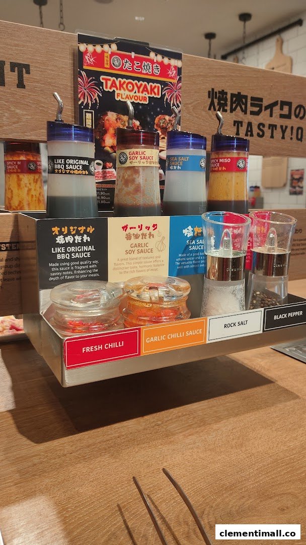 A close-up of Yakiniku Like's condiment station featuring various sauces, spices, and a Takoyaki promotion.