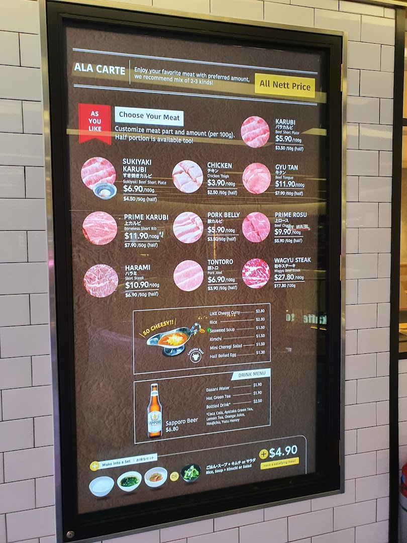 A digital menu board displaying various yakiniku meat cuts, side dishes, and drinks with prices.
