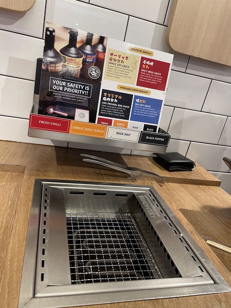 A close-up of a Yakiniku Like dining station featuring sauce and condiment options.