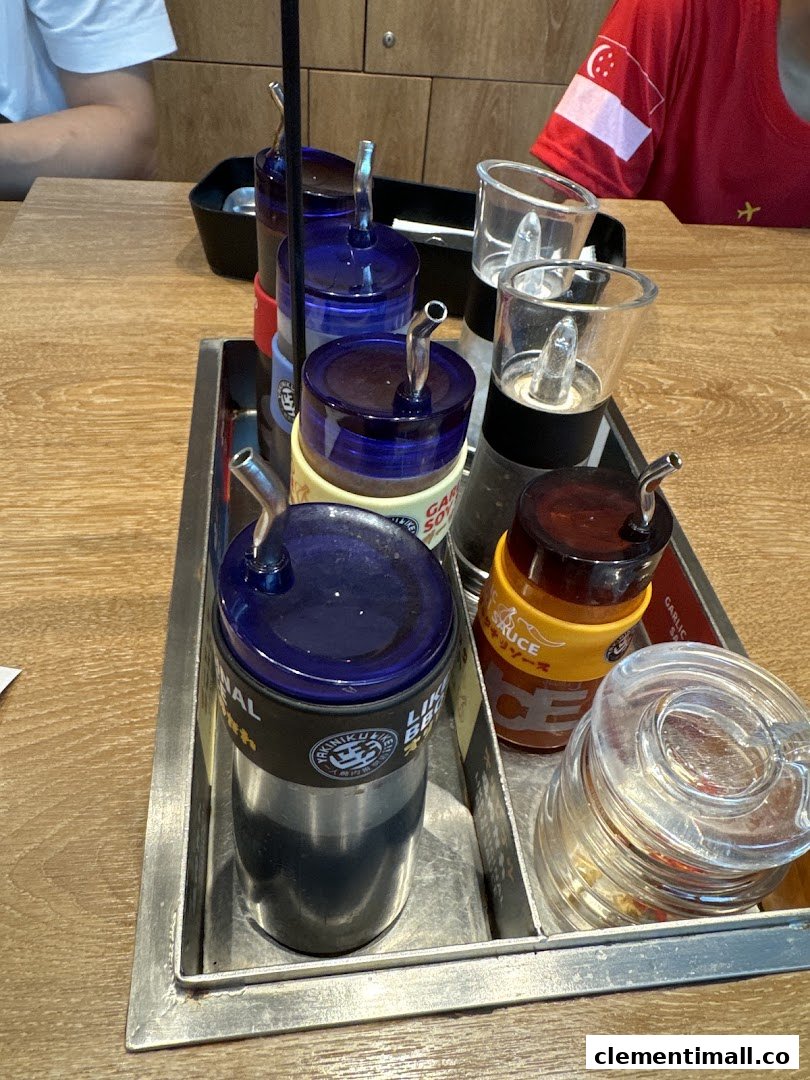 A close-up of a condiment caddy with various sauces, including garlic soy and BBQ, on a wooden table.